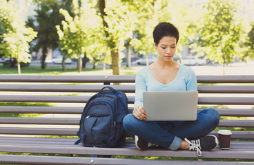 Attractive female freelancer working on a laptop outside