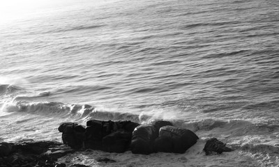 photography in black and white of waves of the sea hitting rocks causing beautiful effect of colors and textures on the beach of macumba in the city of rio de janeiro