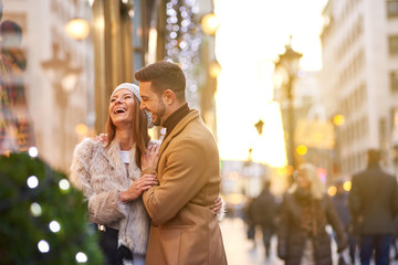 A beautiful young couple walking on the street and checking the storefront with christmas...