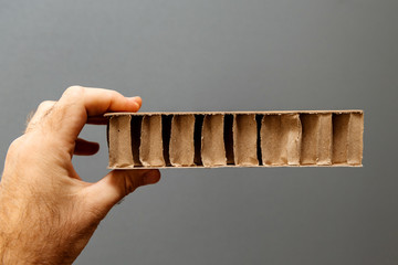 Factory worker male hand inspecting against gray background a corrugated cardboard carton paper for...