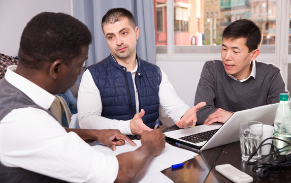 Three seriouse men are working with project on laptop together