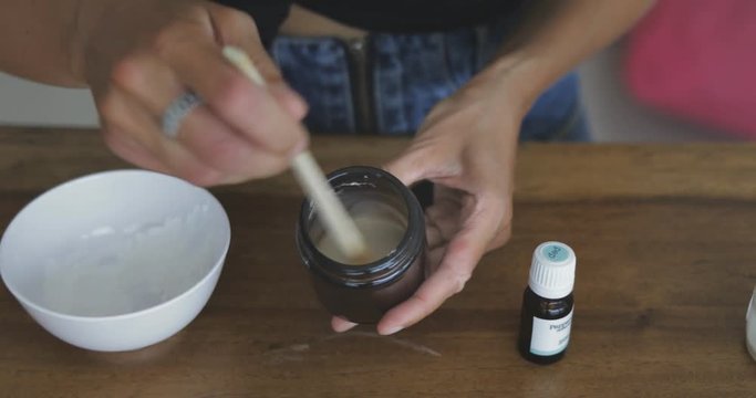 Young pretty woman makes toothbrush independently from ecological natural materials at home. Close-up of footage of girl stirring ingredients in jar. Zero waste concept