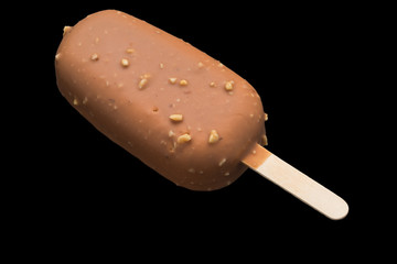 Ice cream on stick covered with chocolate and nuts
