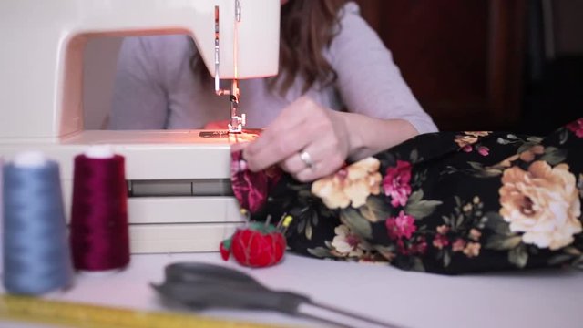 Close-up female hands sewing fabric on sewing machine