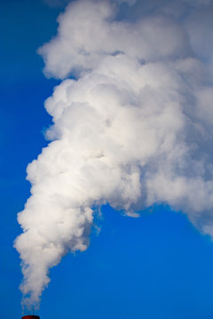 smoke from a pipe in the factory against a blue sky