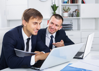 two young males coworkers working in firm office