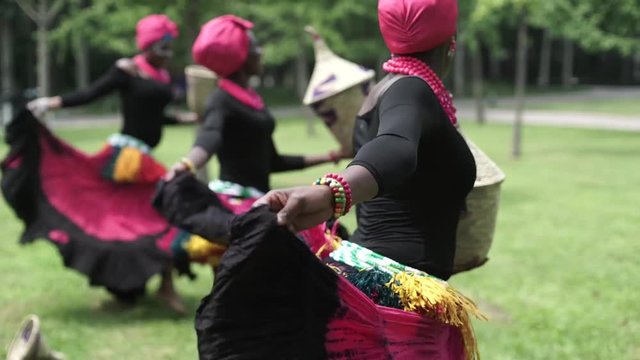 Three african women dancing folk dance in traditio.costumes with coats of skirts