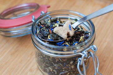 dry tea leaves on a spoon with a slice of sugar