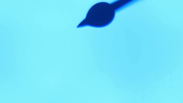An arty macro of a transparent blob of liquid getting bigger and nosediving at last. A water stream dribs after in a turquoise aboratory.