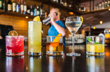 Drinks on a bar as bartender shakes drink