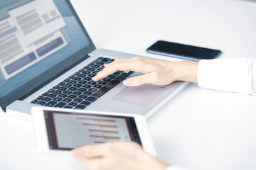Typing on laptop keyboard. Close-up of a young woman holding brush in her hand and applying makeup. Isolated on light blue background.