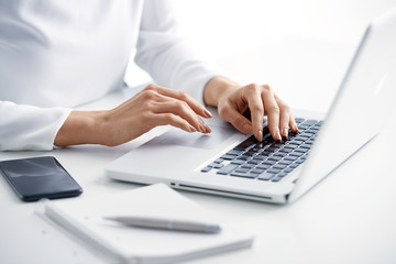 Typing on laptop keyboard. Close-up of a young woman holding brush in her hand and applying makeup....