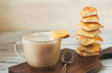 Appetizing picture of food, a cup with fragrant coffee, mocha, milk on a turret background of a square homemade cookie