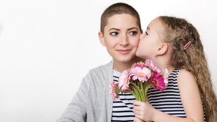 Happy Mother's Day, Women's day or Birthday background. Cute little girl giving mom, cancer survivor,  bouquet of pink gerbera daisies. Loving mother and daughter.