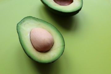 Cut in half avocado on a green background