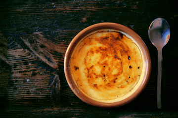 Typical "crema catalana" served on a clay plate on a rustic wooden table with a spoon. Empty copy space for Editor's text.