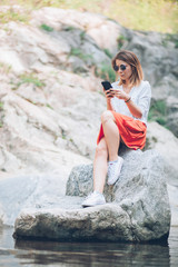 Young woman usin smartphone on the lake in the springtime