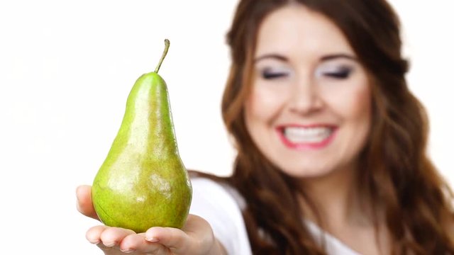 Smiling woman holding and recommend to eat pear fruit, isolated on white. Focus on pear. Healthy eating, vegan food, dieting concept.