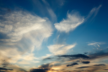 Background of transparent white clouds in a light blue sky illuminated by the sun.