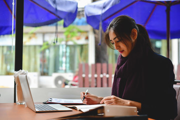 Business Concept.Young Asian businesswoman is working happily.Young businesswoman working in a cafe.Young businesswoman is relaxation in a coffee shop.