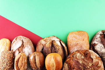 Different kinds of bread and bread rolls on board from above. Kitchen or bakery poster design