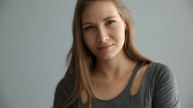 portrait of a blond girl of European appearance in casual clothes on a gray background