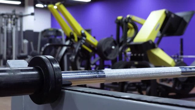 Closeup on an unloaded barbell on a rack in a gym