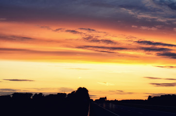 Empty asphalt road and sun rising on skyline. Colorful sunset over road. Minimalist style design. Nature background, landscape with copy space. Banner