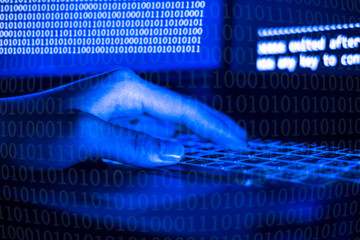 A computer programmer or hacker prints a code on a laptop keyboard to break into a secret organization system.