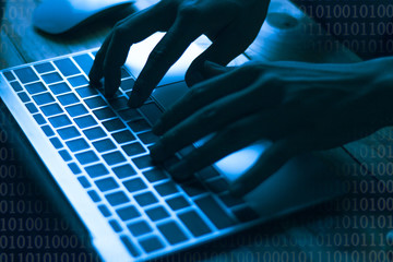 A computer programmer or hacker prints a code on a laptop keyboard to break into a secret organization system.