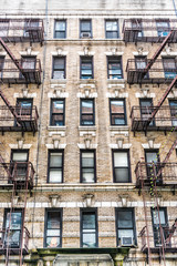 Old apartment condo building exterior architecture in Chelsea, NYC, Manhattan, New York City with fire escapes, windows, ladders