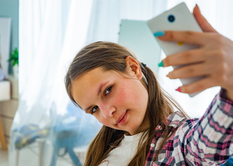 Cute teenager girl making selfie on a smartphone Indoors in room