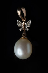 Gold pendant with a pearl on a black background