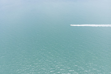 Aerial view of the sea with a motorboat crossing the ocean with white trace