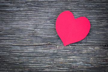Red heart from a paper lies on an old board