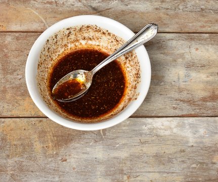Spoonful of rich dark spicy marinade in a white bowl