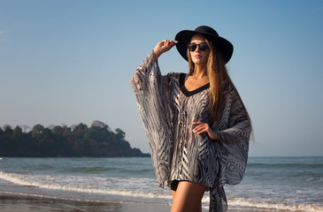 Beautiful, elegant girl, model strolls along the seashore. Lifestyle, style, fashion, beauty.