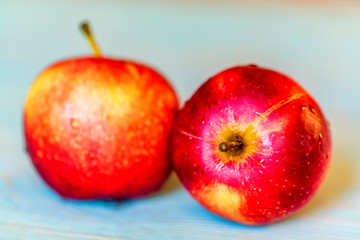 Two whole red apples on blue wooden surface