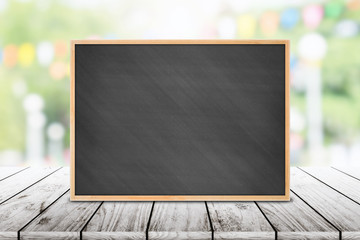 Empty  Chalkboard on outdoors wooden table with party in garden background blurred.