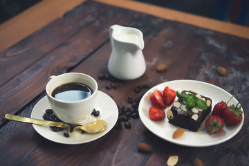 Hot coffee in white cup on wood background,Brownie with Fresh strawberry on white plate