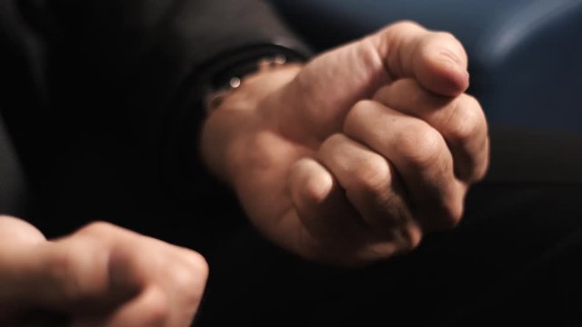 Adult unrecognizable male in black suit hands opens fist to reveal green candy on palm, close up