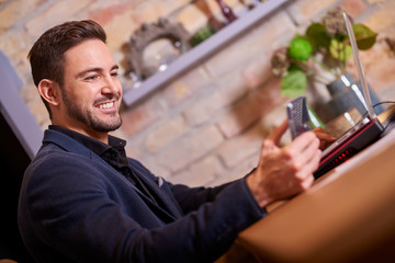 A happy handsome young businessman using his smartphone in office environment.