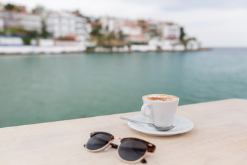 Cup of cofee in a terrace on wooden table with blurred landscape on the background.