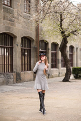 Fototapeta premium A beautiful girl in a cap is walking around the college. A student is enjoying a spring day. She is wearing sunglasses and a backpack.