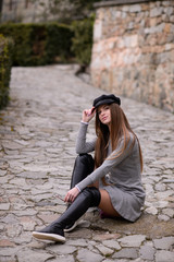 A beautiful girl in a cap is walking around the college. A student is enjoying a spring day.