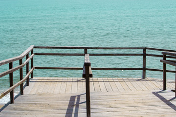 Wooden walkway with railing going to the ocean