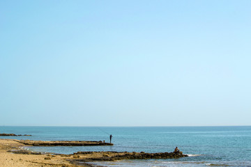 Two men fishing in the sea with rods