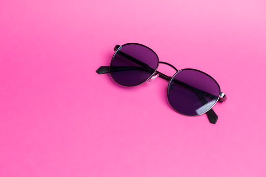 Beautiful sunglasses on pink isolated background close-up