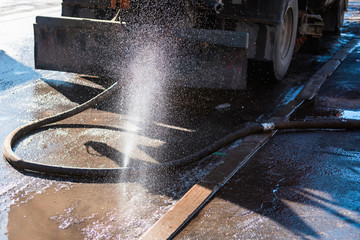The municipal machine pours the road with a damaged hose
