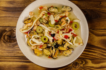 Seafood salad with shrimp, squid and mussels on wooden table